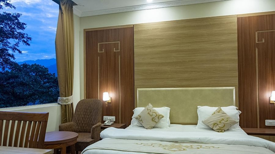 A queen bed with cushioned headboard and lamps on the side in Deluxe Room at Sumitel Gangtok
