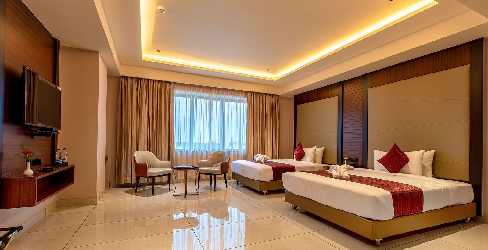 A side view of a room featuring two beds and a seating area in the corner at M Pro Palace.