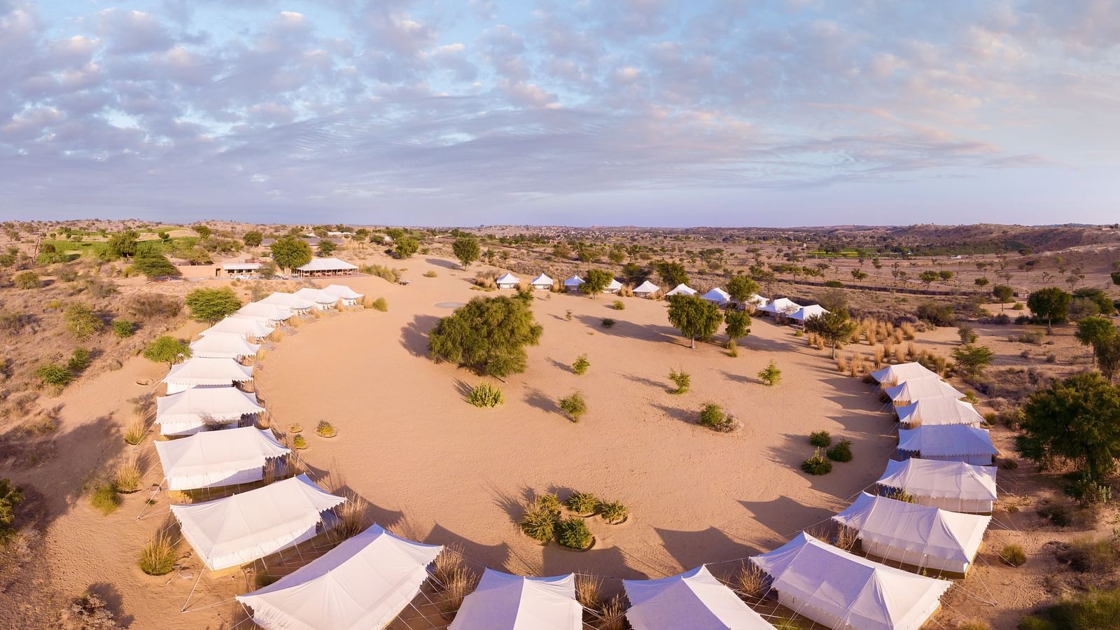  An aerial view of a circular tented camp in the desert, with tents arranged around a central point, creating a harmonious layout - MANVAR Resort & Desert Camp