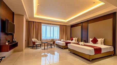 A side view of a room featuring two beds and a seating area in the corner at M Pro Palace.