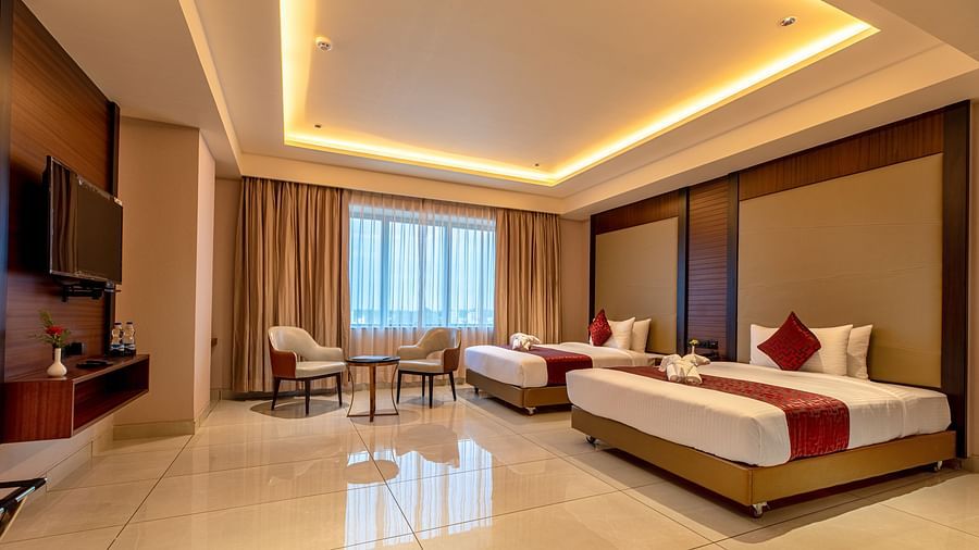 A side view of a room featuring two beds and a seating area in the corner at M Pro Palace.