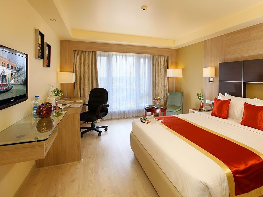 A stylish and well-lit bedroom featuring a plush king-size bed, a sleek workstation, and warm wooden tones. - La Classic, Hosur Road