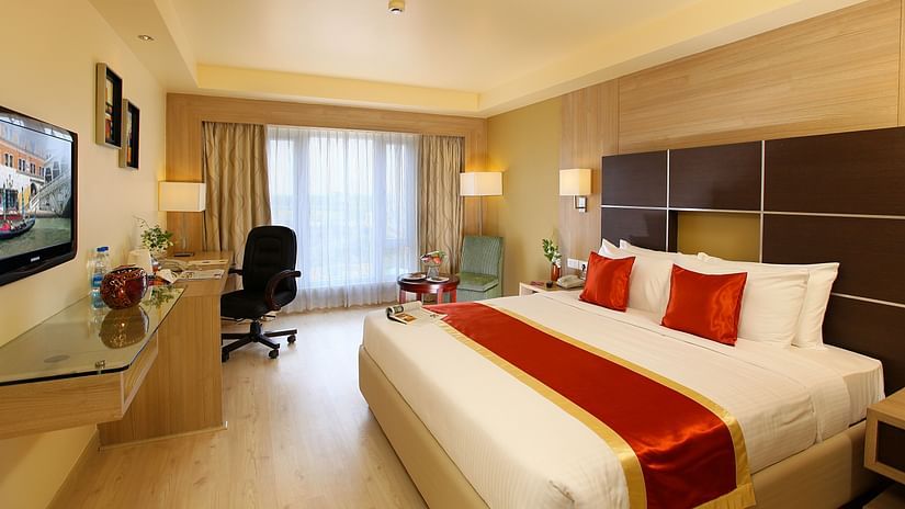 A luxurious hotel room with a king-size bed, modern décor, a work desk, and a large window offering natural light. - La Classic, Hosur Road