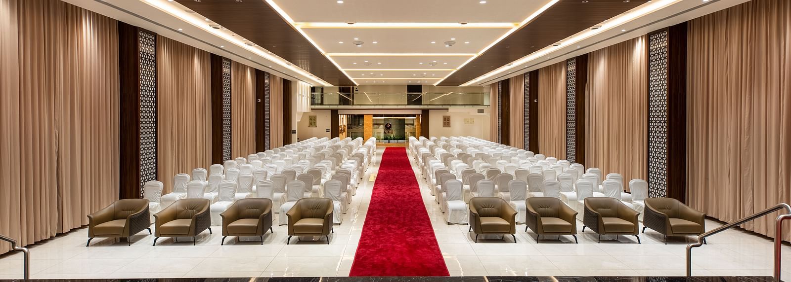 An image of a hall with chairs neatly arranged, with a carpet running between them at M Pro Palace.
