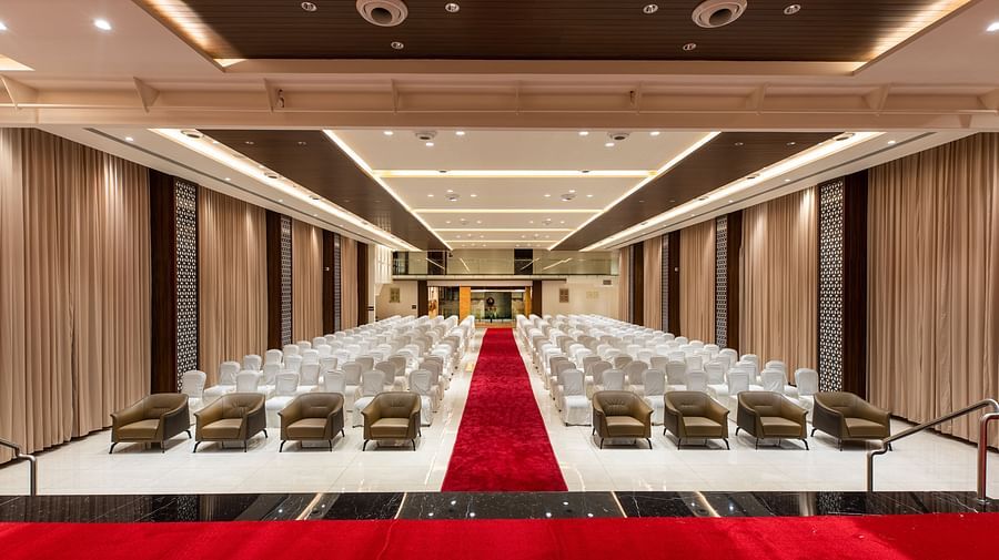 An image of a hall with chairs neatly arranged, with a carpet running between them at M Pro Royal.