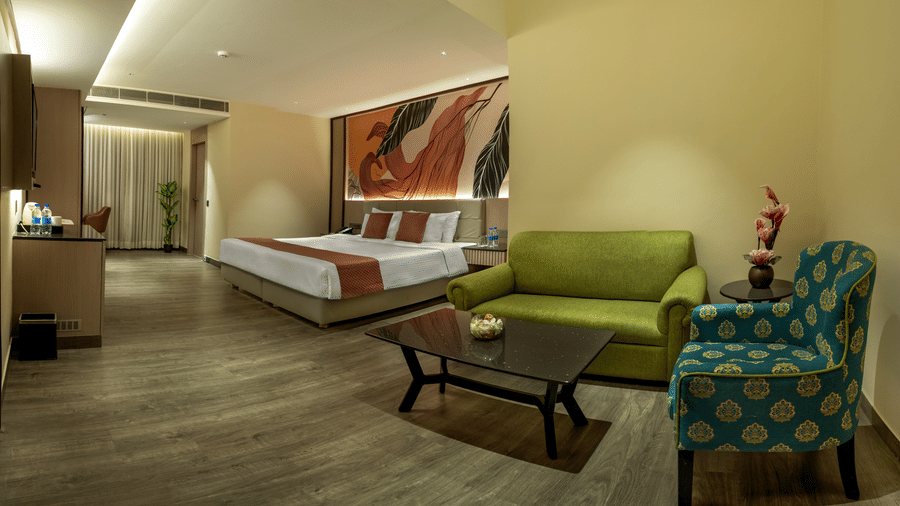 Spacious guest room with king bed, lounge seating and modern decor at The Sonnet, Jamshedpur.