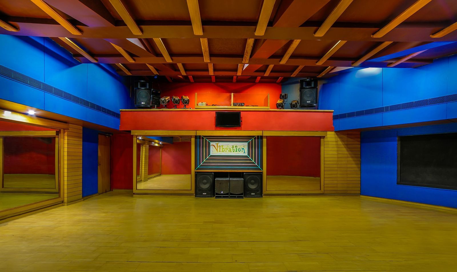 A vibrant dance hall with a warm wooden ceiling, colorful lighting, and an open floor space. - Tara, Comfort Hotel in Hyderabad - Ramoji Film City.