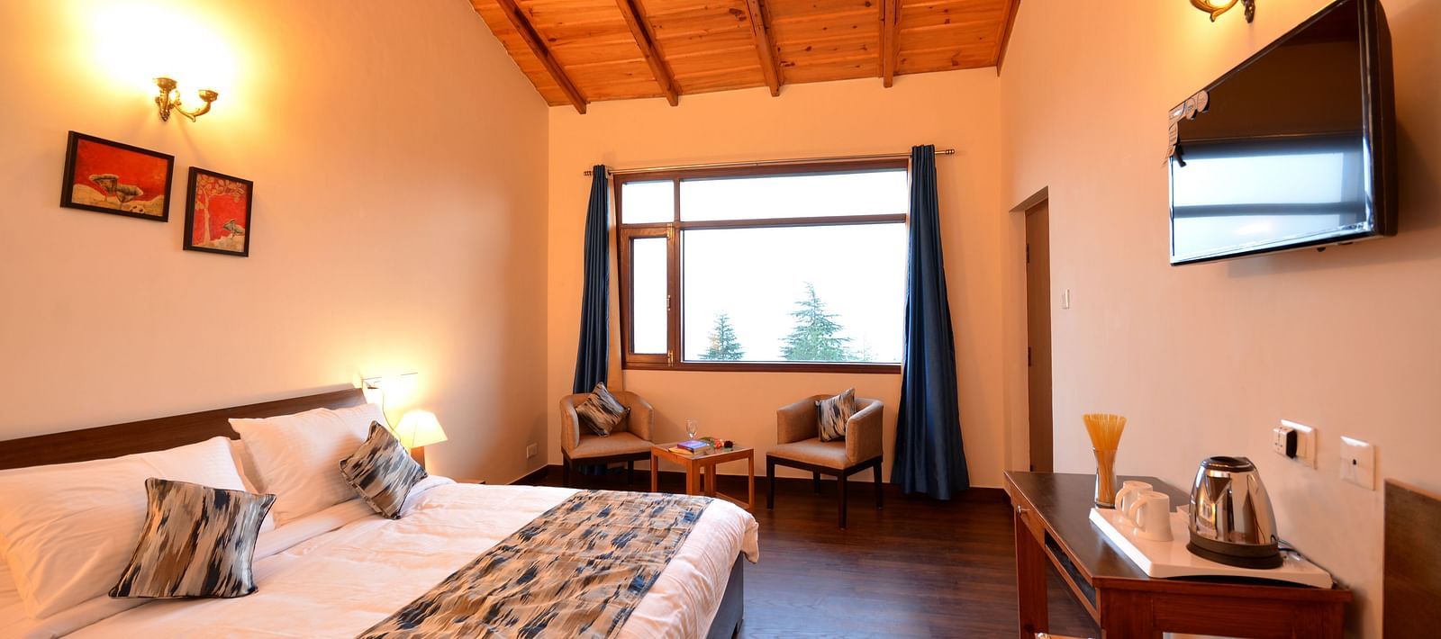 A spacious room in Shitlakhet featuring a comfortable bed and large windows overlooking greenery - BluSalzz Escapade - Anant Rasa Resort