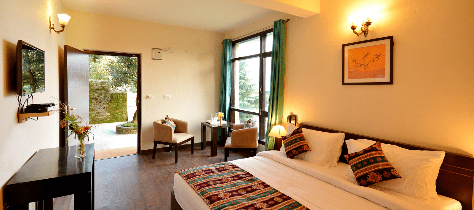 A brightly-lit room with a king size bed, wooden furniture, and large windows offering scenic views - BluSalzz Escapade - Anant Rasa Resort