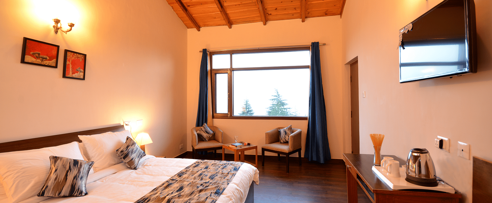A spacious room in Shitlakhet featuring a comfortable bed and large windows overlooking greenery - BluSalzz Escapade - Anant Rasa Resort