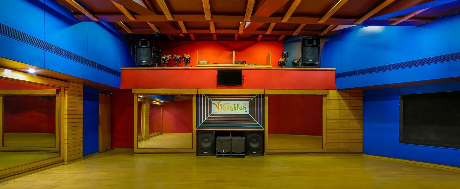 A vibrant dance hall with a warm wooden ceiling, colorful lighting, and an open floor space. - Tara, Comfort Hotel in Hyderabad - Ramoji Film City.