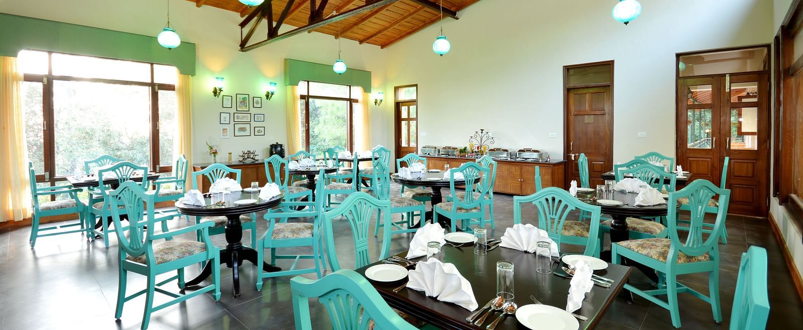 An image of a cafe in Almora with teal coloured chairs, black tables and ambient lighting - BluSalzz Escapade - Anant Rasa Resort