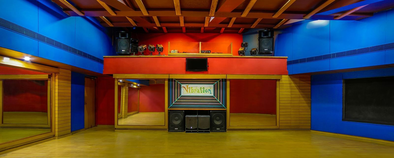 A vibrant dance hall with a warm wooden ceiling, colorful lighting, and an open floor space. - Tara, Comfort Hotel in Hyderabad - Ramoji Film City.