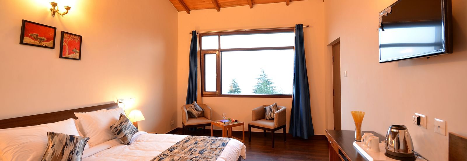 A spacious room in Shitlakhet featuring a comfortable bed and large windows overlooking greenery - BluSalzz Escapade - Anant Rasa Resort