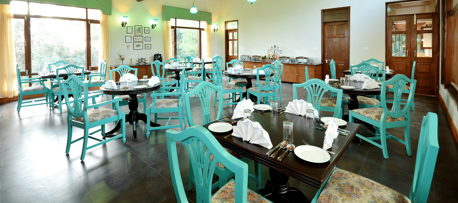 An image of a cafe in Almora with teal coloured chairs, black tables and ambient lighting - BluSalzz Escapade - Anant Rasa Resort