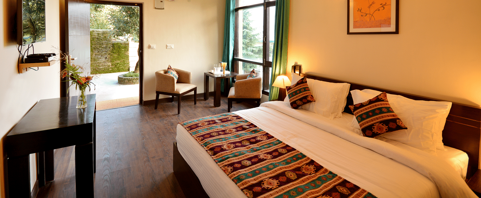 A brightly-lit room with a king size bed, wooden furniture, and large windows offering scenic views - BluSalzz Escapade - Anant Rasa Resort