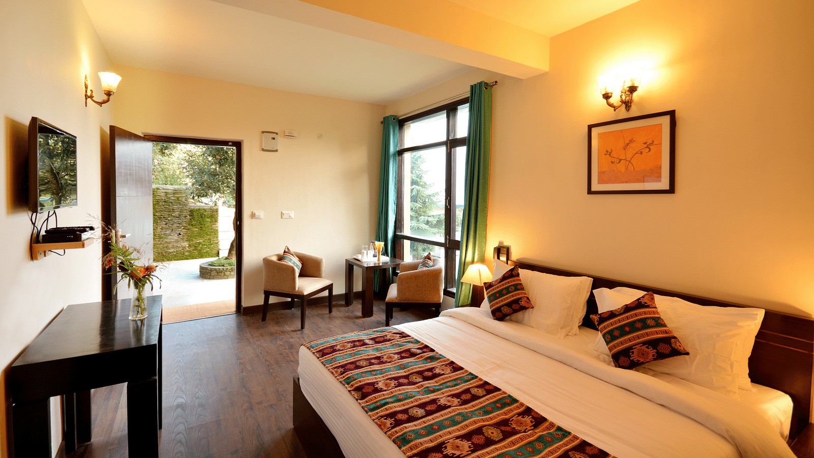 A brightly-lit room with a king size bed, wooden furniture, and large windows offering scenic views - BluSalzz Escapade - Anant Rasa Resort