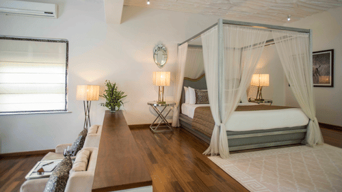 interior of well-equipped rooms at The Serai Bandipur featuring plush bed and lamp next to it with minimalistic decoration giving a rich vibe