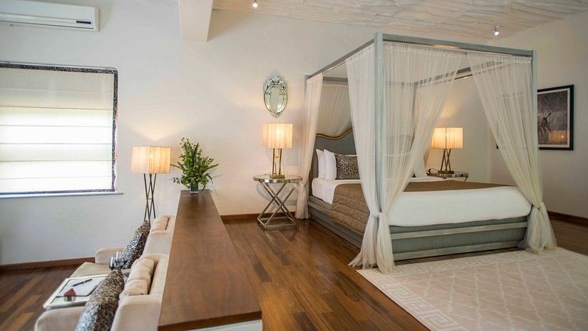 interior of well-equipped rooms at The Serai Bandipur featuring plush bed and lamp next to it with minimalistic decoration giving a rich vibe