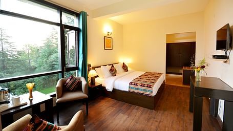 A spacious room in Shitlakhet of Almora District, with a comfortable seating area and expansive views of the outdoors - BluSalzz Escapade - Anant Rasa Resort