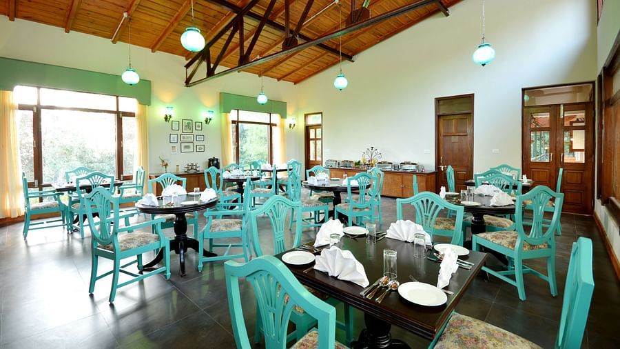 An image of a cafe in Almora with teal coloured chairs, black tables and ambient lighting - BluSalzz Escapade - Anant Rasa Resort