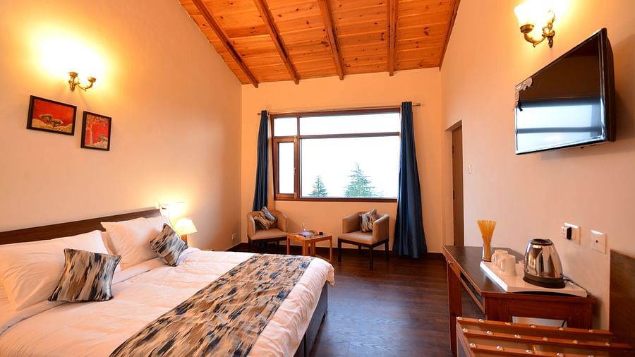 A spacious room in Shitlakhet featuring a comfortable bed and large windows overlooking greenery - BluSalzz Escapade - Anant Rasa Resort