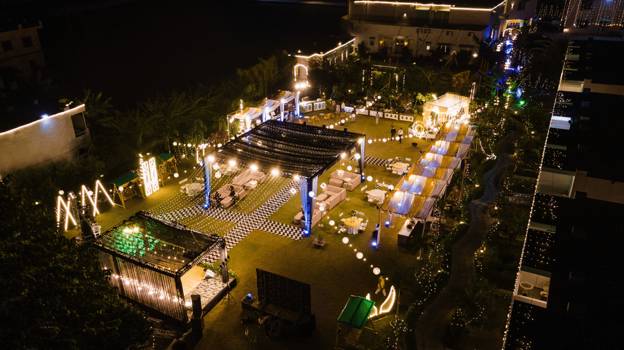 An overhead nighttime shot of a large, festively lit outdoor event or reception space with hanging string lights and decorated tables at Vedikant Resorts The Mallard Corbett.