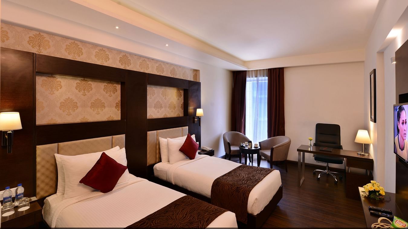 Image of Deluxe Rooms with Twin beds, a TV, chair and table
