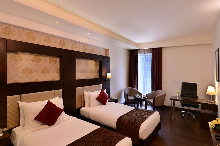 Image of Deluxe Rooms with Twin beds, a TV, chair and table