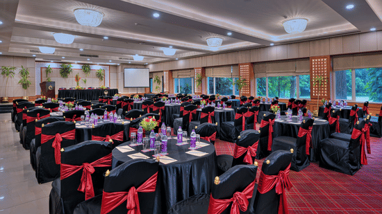 A hall at The Clarks Varanasi, with chairs, tables, and a chandelier.