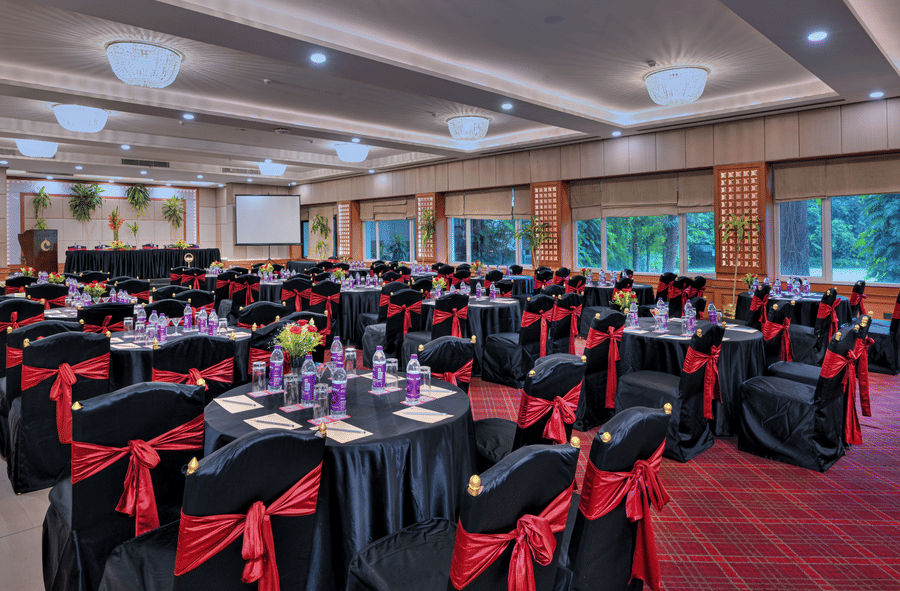 A hall at The Clarks Varanasi, with chairs, tables, and a chandelier.