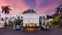 Front view of Jehan Numa Palace in Bhopal at dusk, showcasing the heritage white façade, palm-lined entrance, and vintage cars.