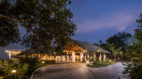 The resort entrance glowing at dusk with a curved driveway and warm ambient lights | Great Trails Wayanad by GRT Hotels
