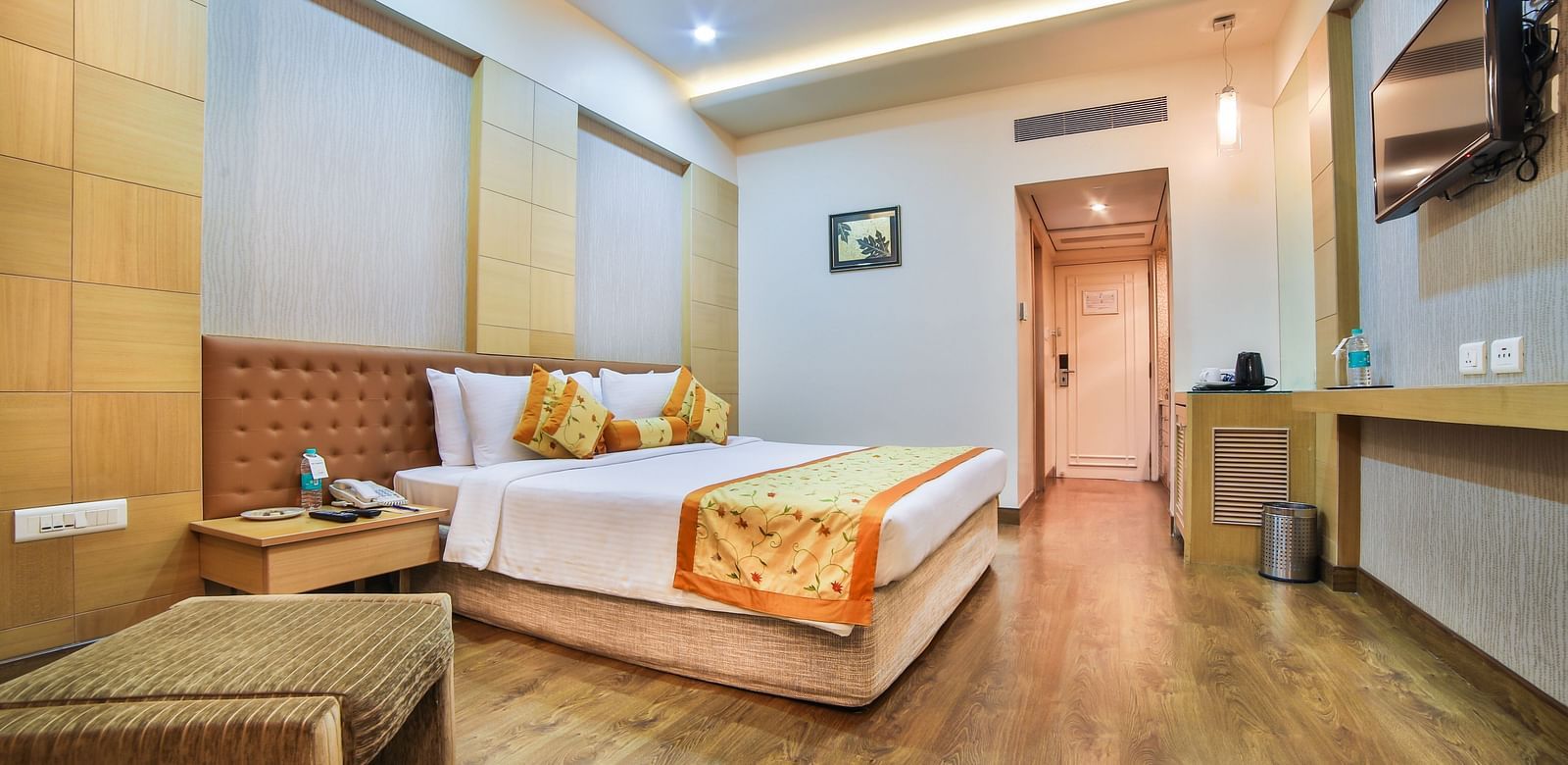 A hotel bedroom with a king bed, warm wood tones, and soft lighting, creating a welcoming space A grand hotel suite with an opulent red and white decor, large bed, and seating area, reflecting a traditional style at Sitara Luxury Hotel in Hyderabad near Ra