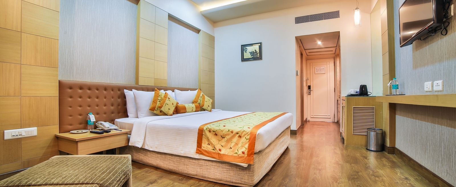 A hotel bedroom with a king bed, warm wood tones, and soft lighting, creating a welcoming space A grand hotel suite with an opulent red and white decor, large bed, and seating area, reflecting a traditional style at Sitara Luxury Hotel in Hyderabad near Ra
