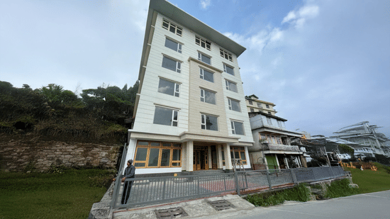 Exterior view of a modern multi-storey building against a hillside backdrop.