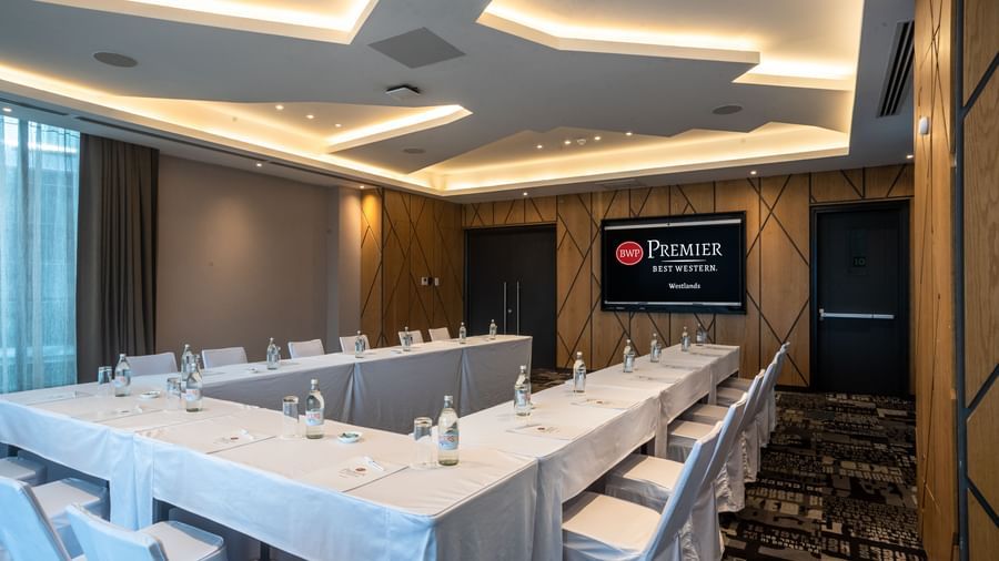 Boardroom at Best Western Premier Westlands hotel, featuring rectangular tables with white cloths, executive chairs, and a large wall-mounted display.