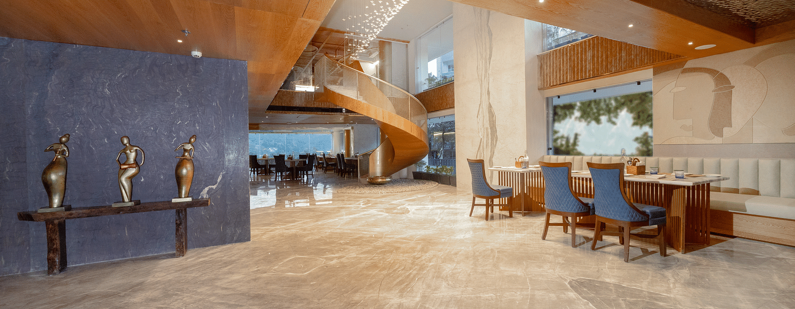 Image of a dining space with tables and chairs and a spiral staircase behind at Auradoon, Dehradun.