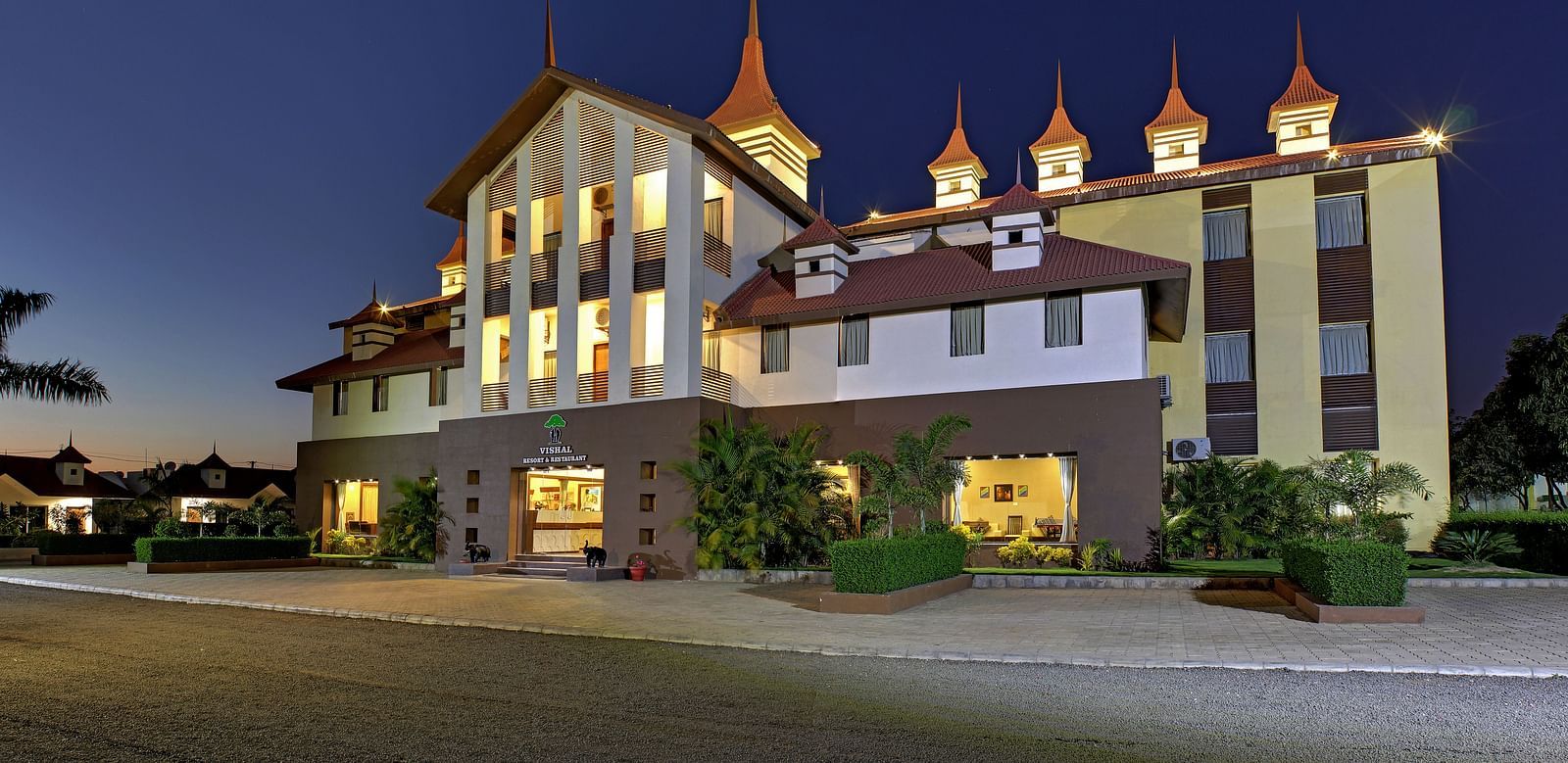 Exterior view of a our hotel building during late evening, illuminated with warm lights - Vishal Lords Inn Gir Forest