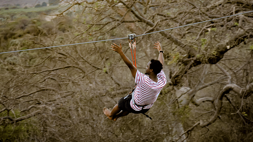 A man enjoying ziplining through the woods.