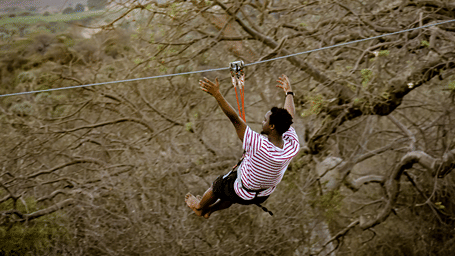 A man enjoying ziplining through the woods.