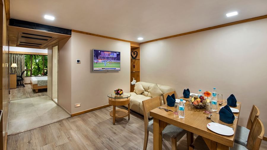 Hotel room hallway leading to a table with amenities, a TV, and a view of the garden - Lords Inn Vadodara