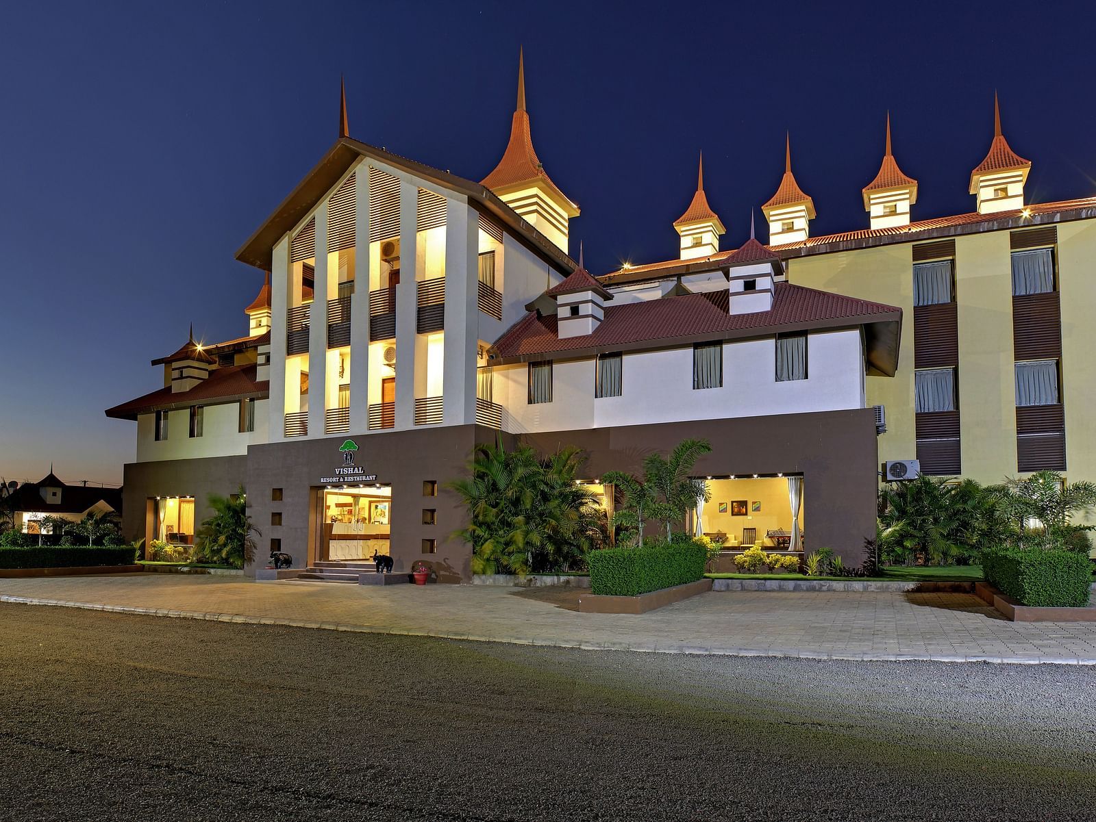 Exterior view of a our hotel building during late evening, illuminated with warm lights - Vishal Lords Inn Gir Forest