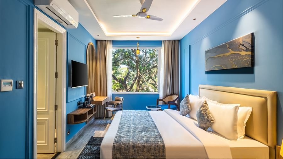 A side view of the bed with bedding in a blue colored room | Renest Calangute, Goa