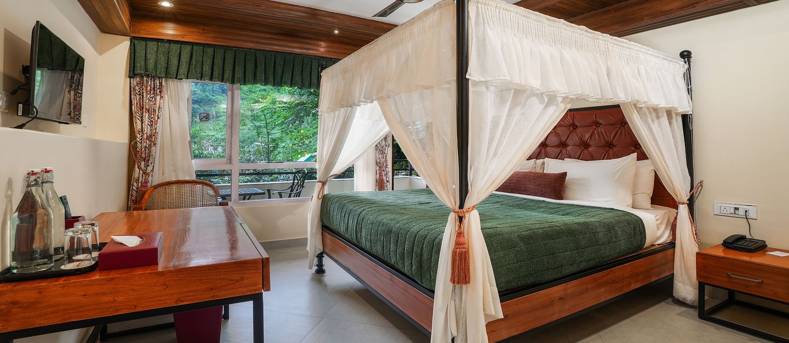 Premium Room with Balcony featuring a large bed with curtains neatly tied to rods on all four sides and a wall-mounted television