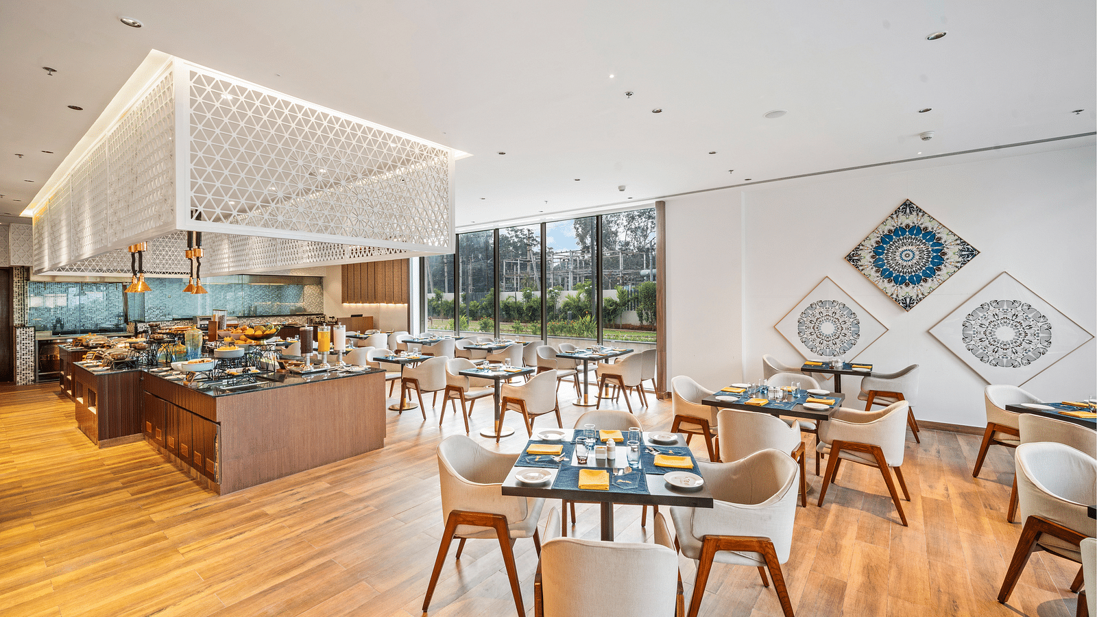 A dining area set with chairs and tables at Grand Vijayawada by GRT Hotels, with modern and sleek interior.