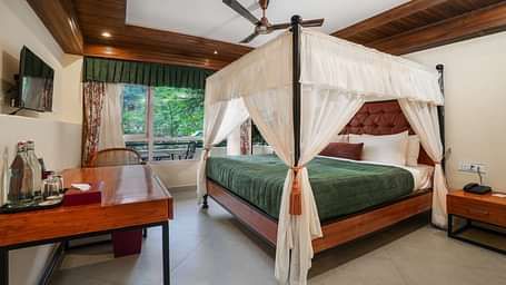 Premium Room with Balcony featuring a large bed with curtains neatly tied to rods on all four sides and a wall-mounted television