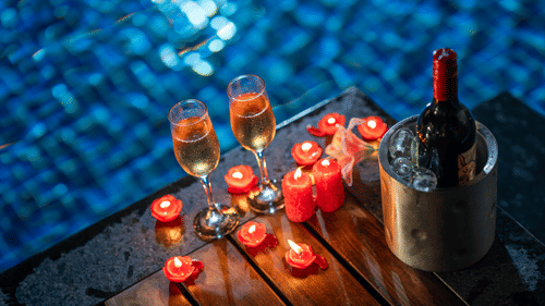 Candles along with beverages arranged on the table by the pool at Uday Backwater Resort
