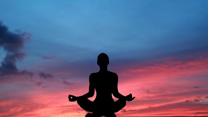 woman performing yoga whilst the sunset