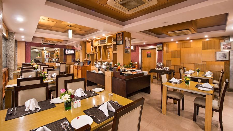 A view of the hotel's dining area with warmly lit tables and chairs - Lords Eco Inn Dahej